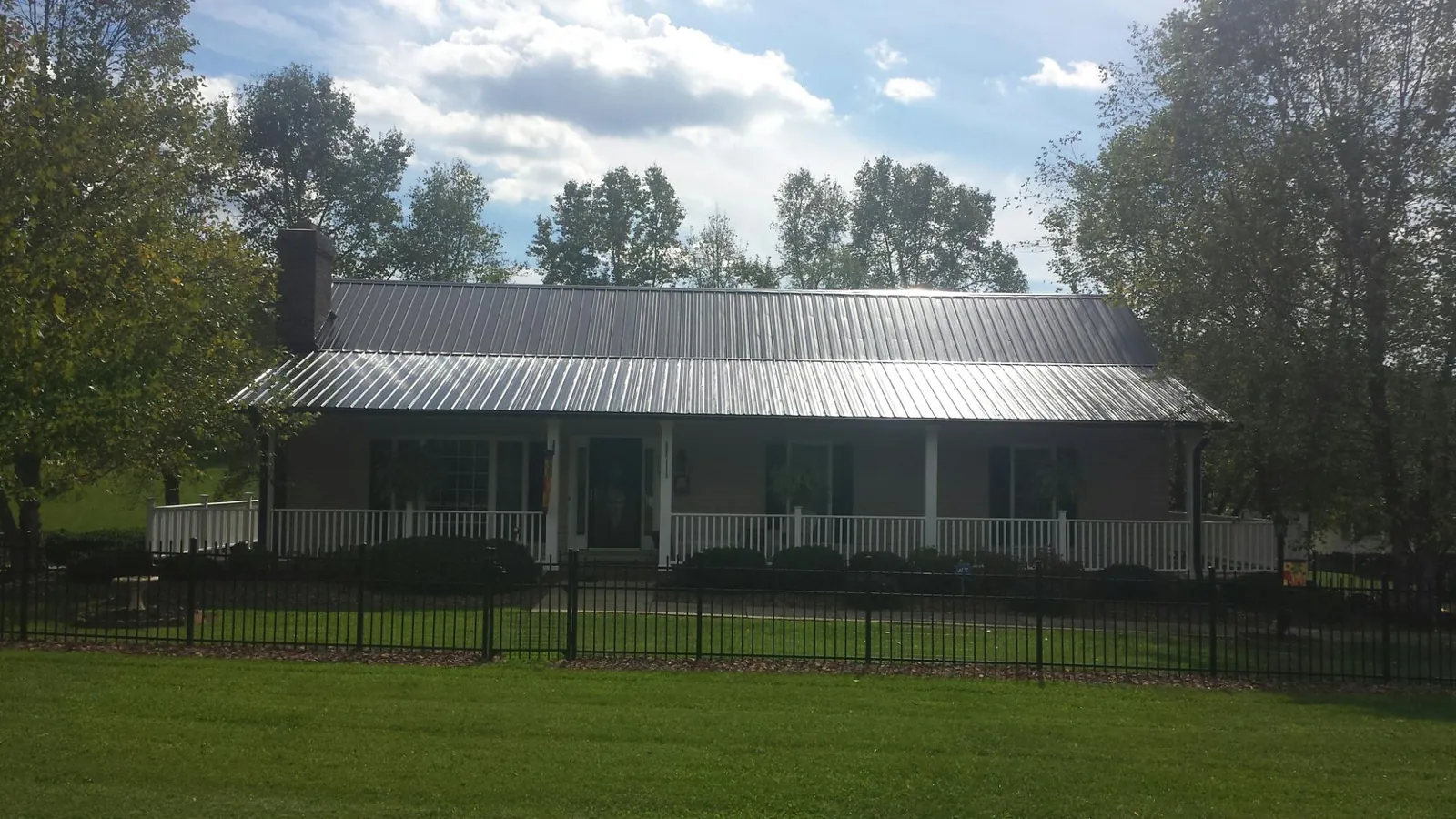 Gray metal roof on a brick ranch with a full width front porch — Gutter Guard Installation work by our crew in Granby